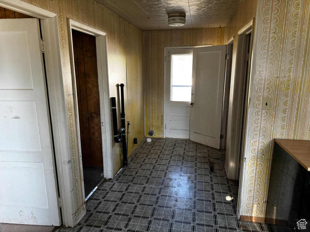 Corridor with wooden walls and dark tile flooring