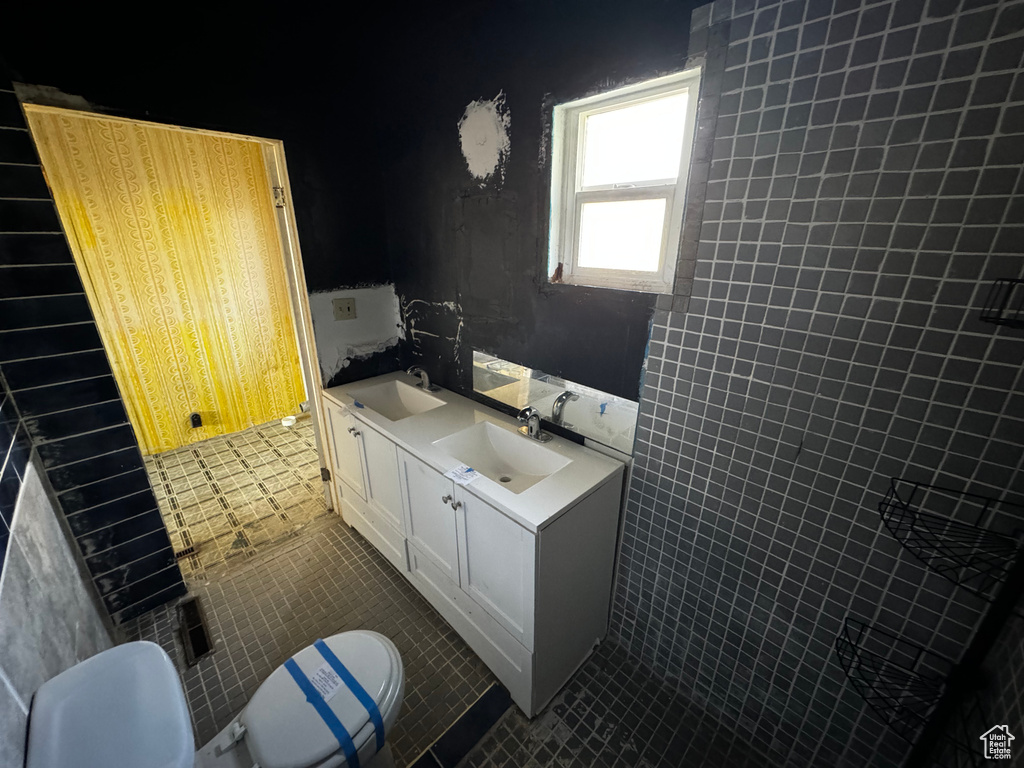 Bathroom with oversized vanity, tile walls, toilet, and tile floors