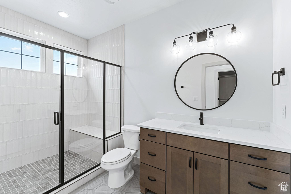 Bathroom with tile floors, walk in shower, vanity, and toilet