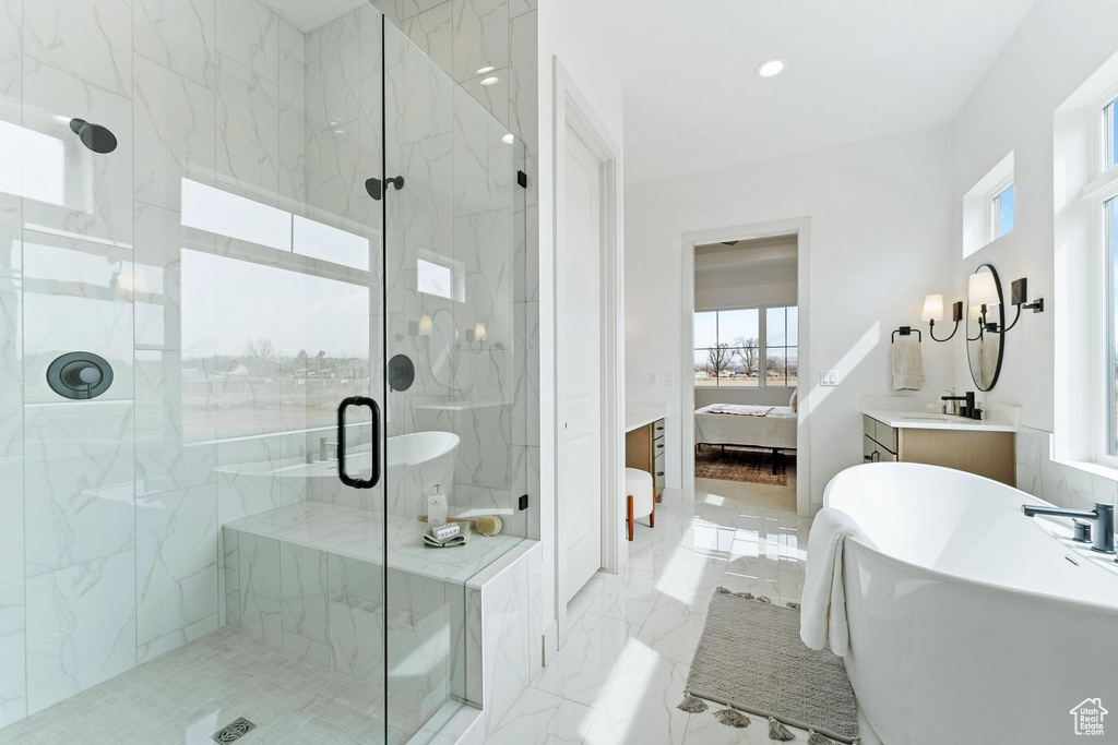 Bathroom featuring tile flooring, tile walls, separate shower and tub, and vanity