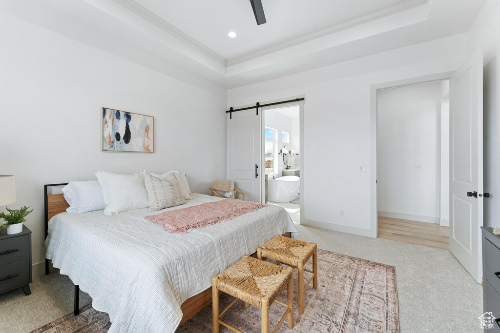 Carpeted bedroom with ensuite bathroom, a barn door, ceiling fan, and a raised ceiling