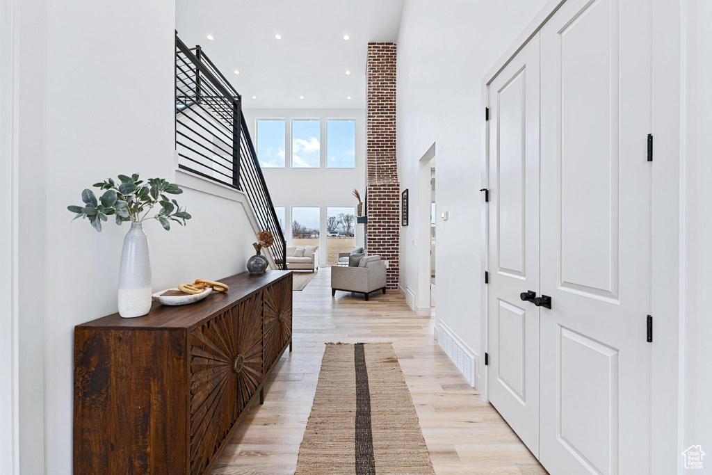 Hall with a towering ceiling and light hardwood / wood-style flooring