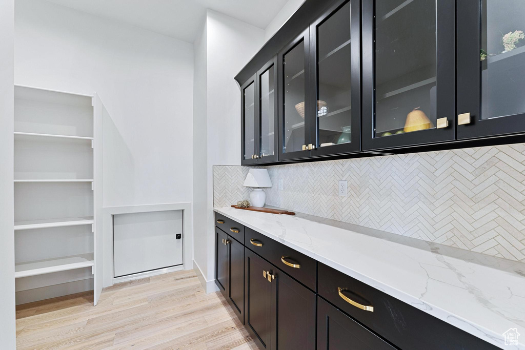 Interior space with light stone countertops, tasteful backsplash, and light hardwood / wood-style flooring