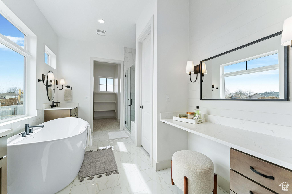 Bathroom featuring vanity, tile flooring, plenty of natural light, and plus walk in shower