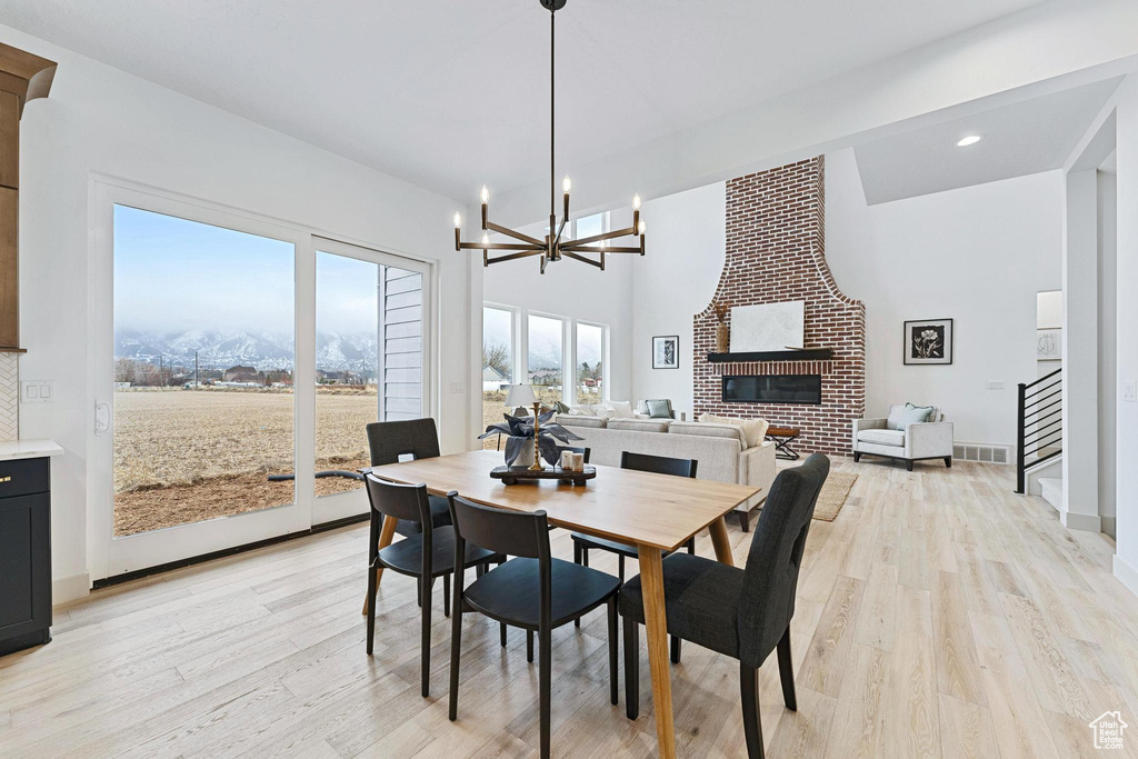 Dining area featuring a notable chandelier, brick wall, a brick fireplace, and light hardwood / wood-style flooring