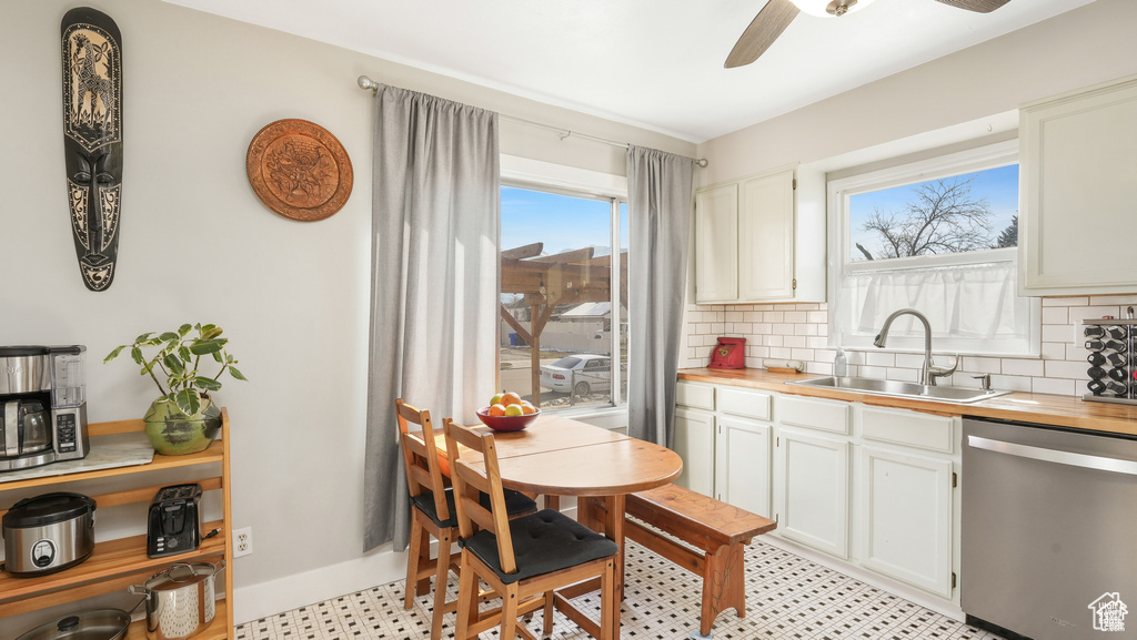 Kitchen featuring light tile flooring, ceiling fan, tasteful backsplash, white cabinetry, and stainless steel dishwasher