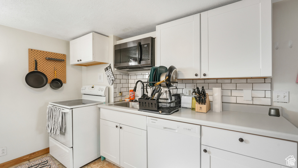 Interior space featuring white cabinetry, white appliances, light tile floors, and tasteful backsplash