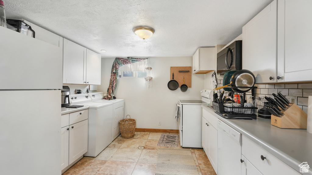 Interior space with washing machine and clothes dryer, a textured ceiling, and light tile floors