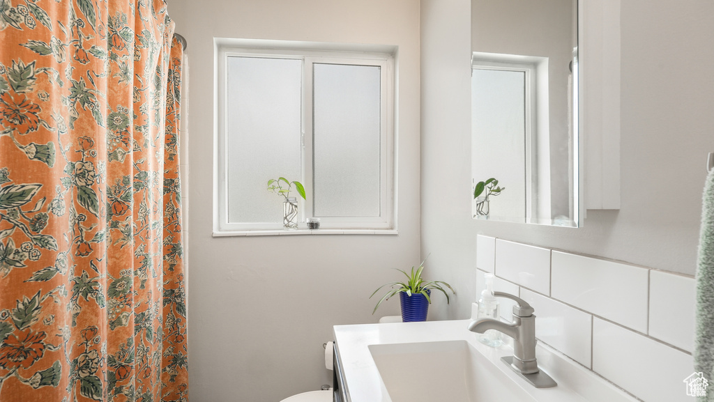 Bathroom featuring vanity with extensive cabinet space and toilet