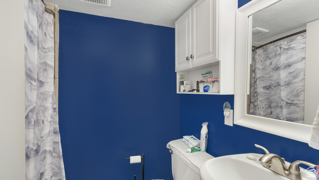 Bathroom with sink, toilet, and a textured ceiling