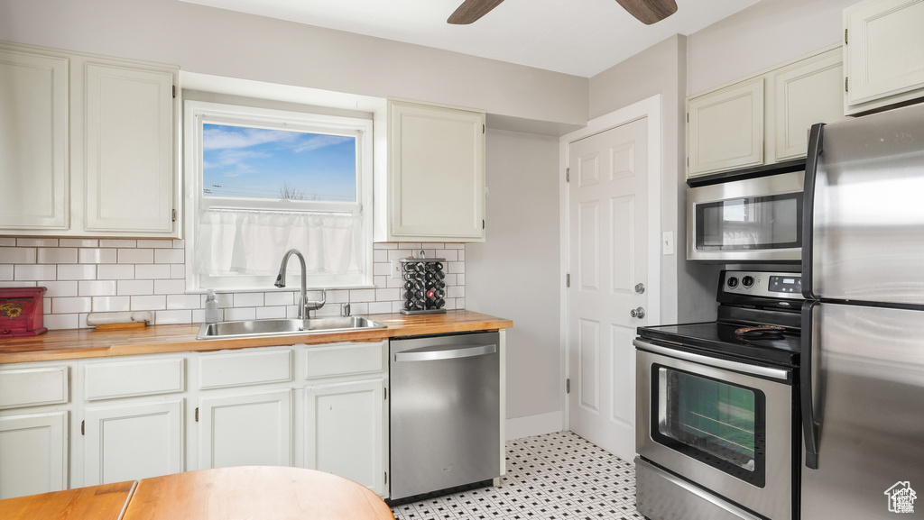 Kitchen with ceiling fan, light tile flooring, backsplash, sink, and appliances with stainless steel finishes