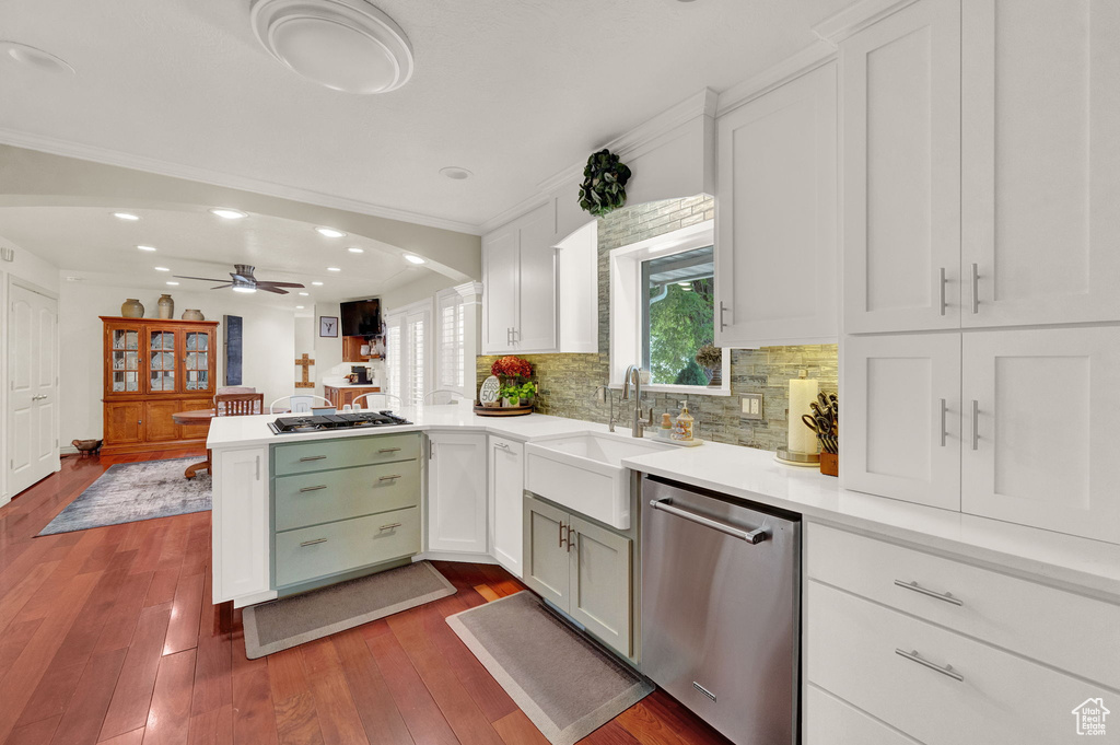 Kitchen featuring appliances with stainless steel finishes, hardwood / wood-style flooring, white cabinets, kitchen peninsula, and ceiling fan