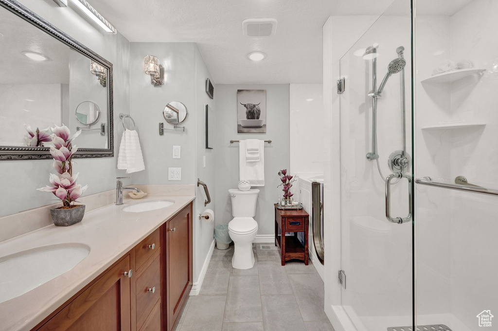 Bathroom featuring tile floors, an enclosed shower, toilet, and vanity with extensive cabinet space