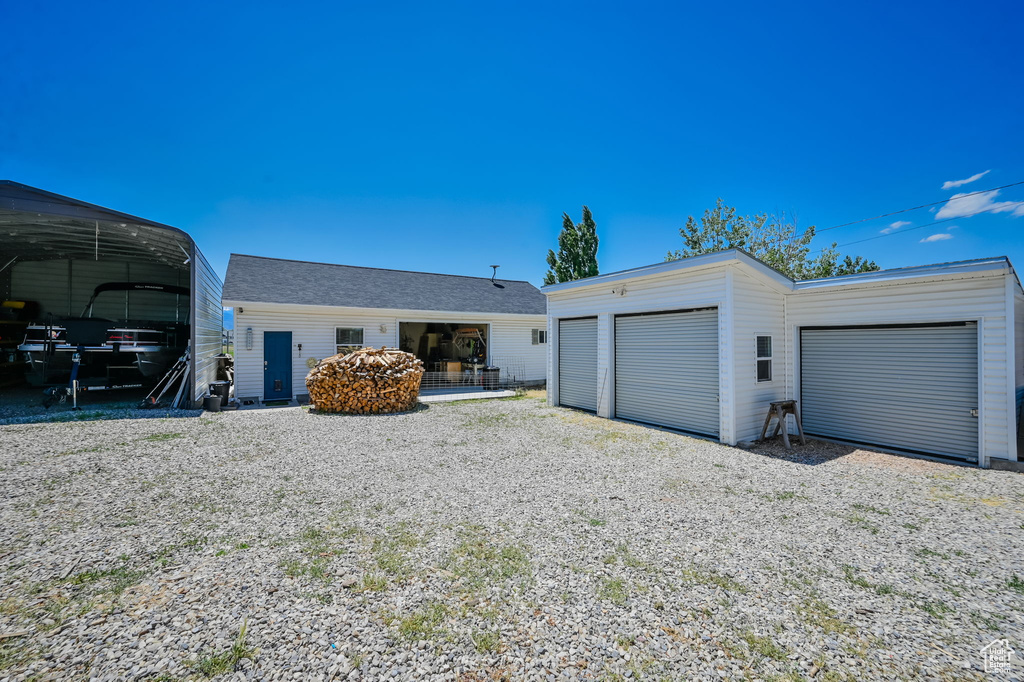 View of front of home with an outdoor structure, a garage, and a carport