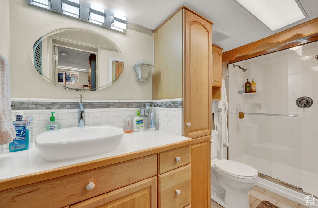 Bathroom featuring an enclosed shower, tile flooring, tasteful backsplash, and vanity with extensive cabinet space