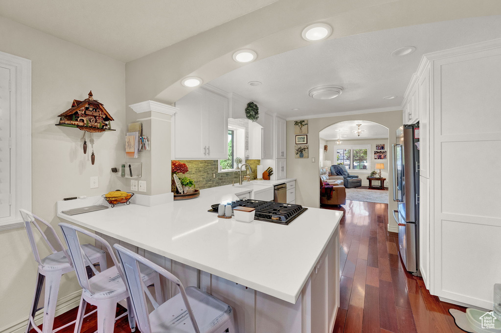 Kitchen with dark hardwood / wood-style floors, ornamental molding, a healthy amount of sunlight, and kitchen peninsula