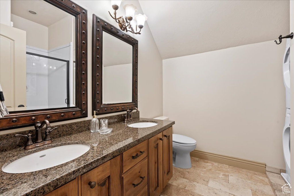 Bathroom featuring vanity with extensive cabinet space, dual sinks, toilet, tile floors, and lofted ceiling