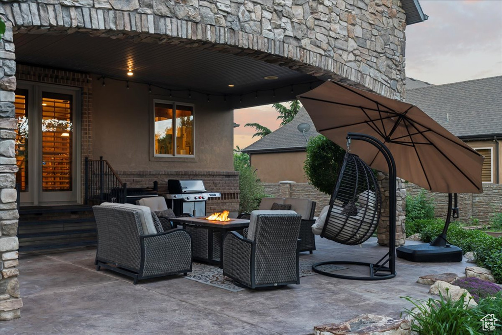 Patio terrace at dusk with an outdoor living space with a fire pit and area for grilling