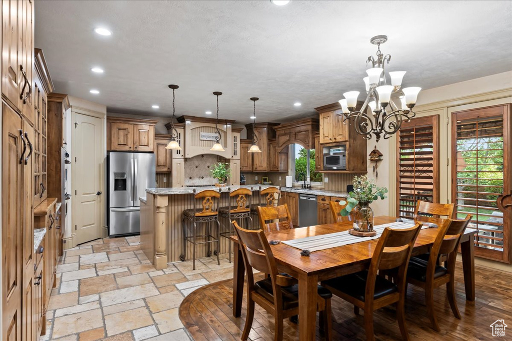 Dining area with a notable chandelier, sink, and light tile floors