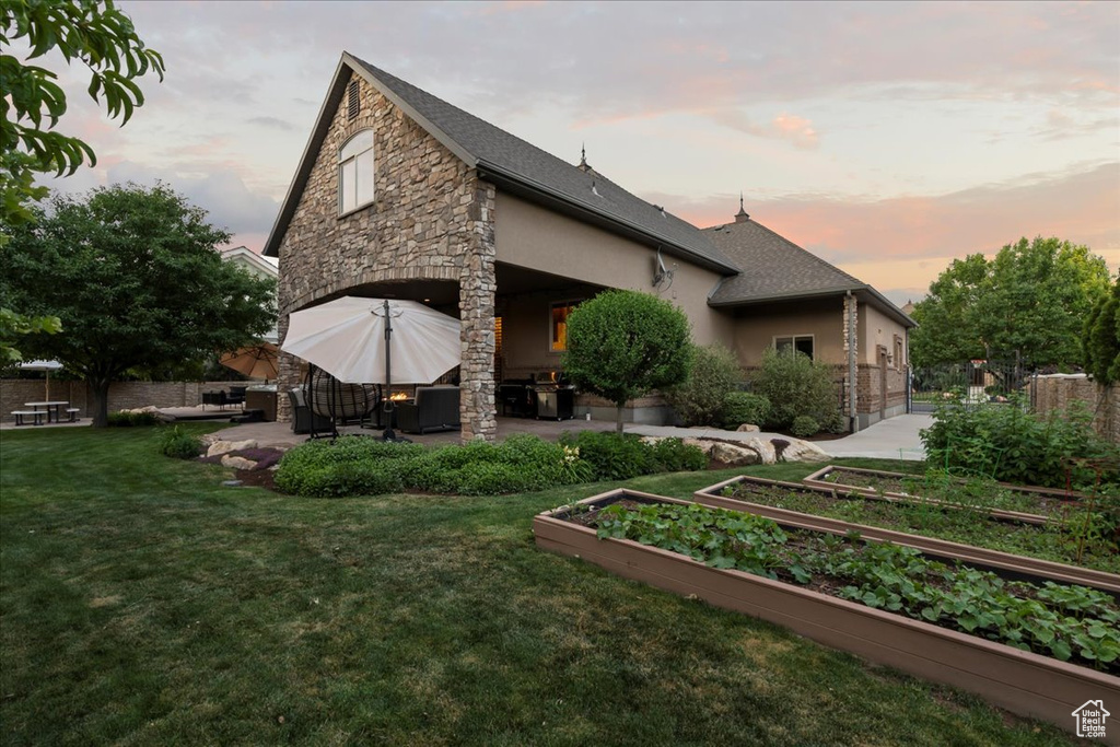 Back house at dusk featuring a patio area and a yard