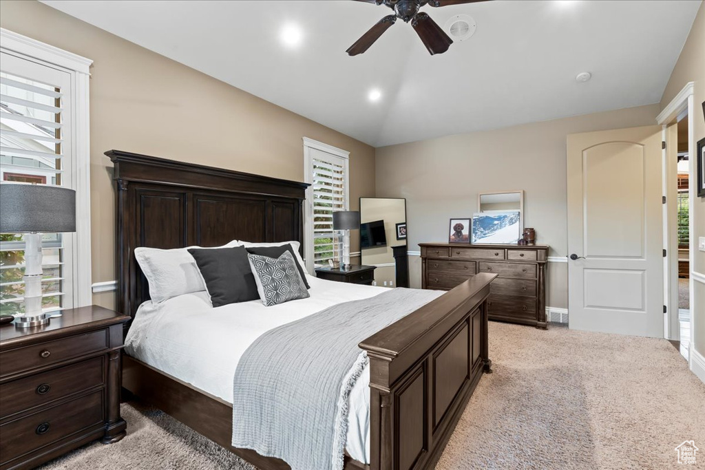 Carpeted bedroom featuring multiple windows, vaulted ceiling, and ceiling fan