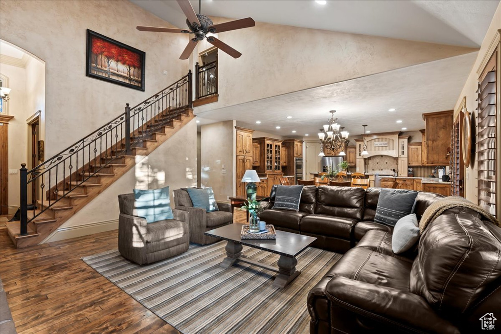 Living room featuring high vaulted ceiling, ceiling fan with notable chandelier, and hardwood / wood-style floors