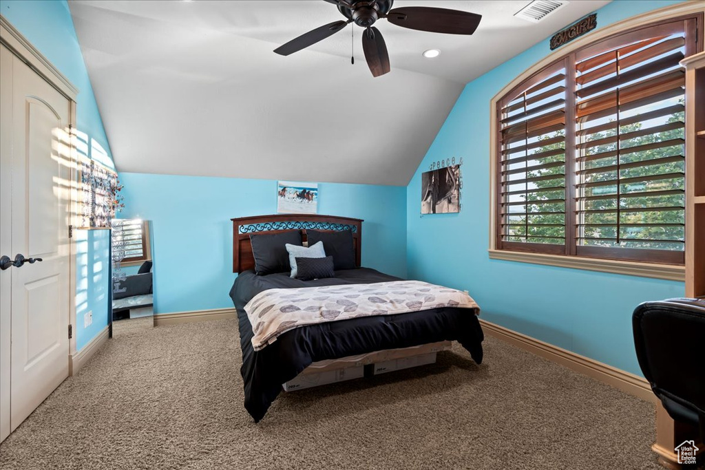 Bedroom with carpet floors, ceiling fan, and vaulted ceiling