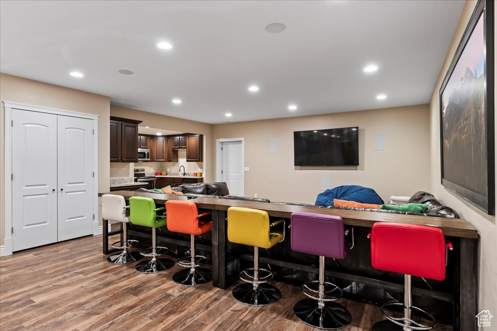 Kitchen featuring kitchen peninsula, a kitchen breakfast bar, hardwood / wood-style flooring, electric range, and dark brown cabinets