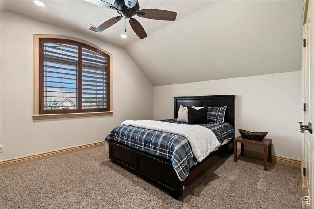 Carpeted bedroom featuring ceiling fan and vaulted ceiling