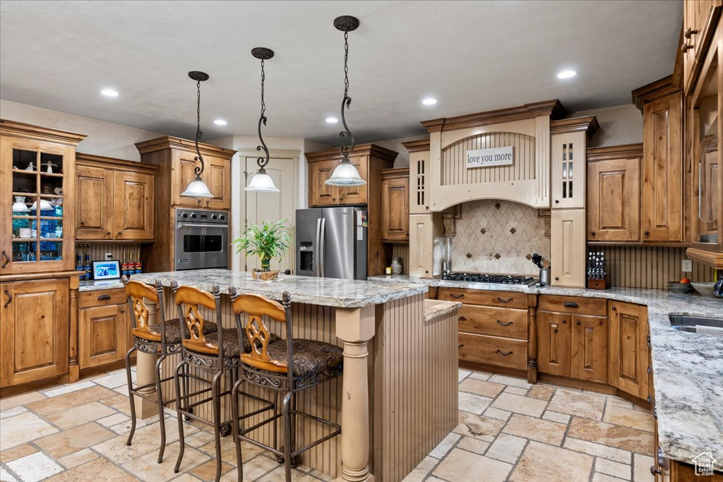 Kitchen featuring stainless steel appliances, light tile floors, a center island, and backsplash