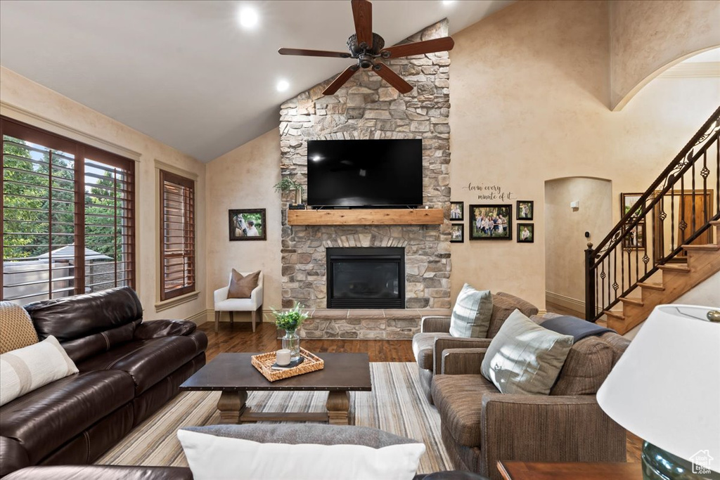 Living room with high vaulted ceiling, hardwood / wood-style floors, ceiling fan, and a fireplace