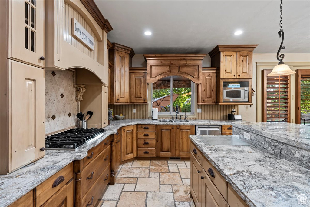 Kitchen with decorative light fixtures, backsplash, light tile floors, sink, and appliances with stainless steel finishes