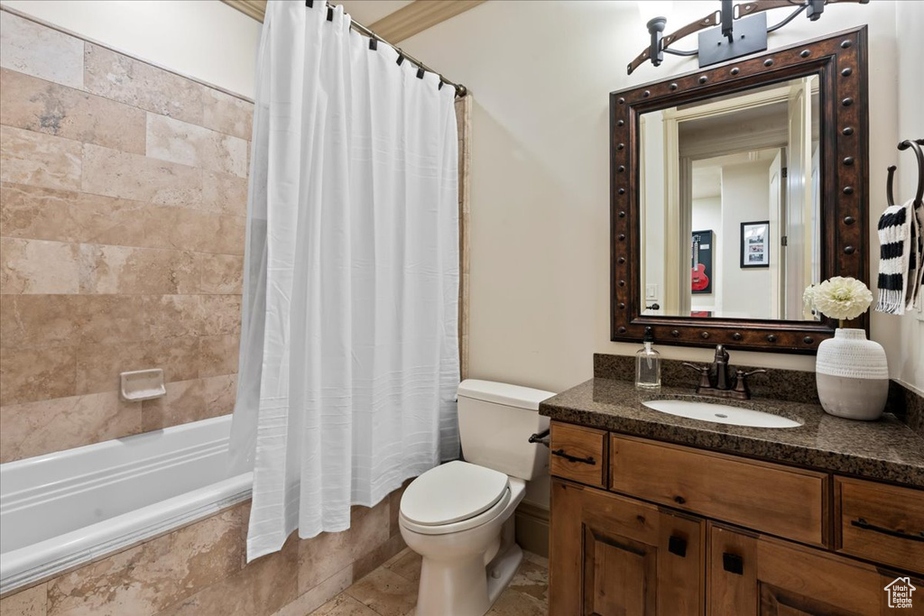 Full bathroom featuring shower / bath combo with shower curtain, vanity, toilet, and tile floors