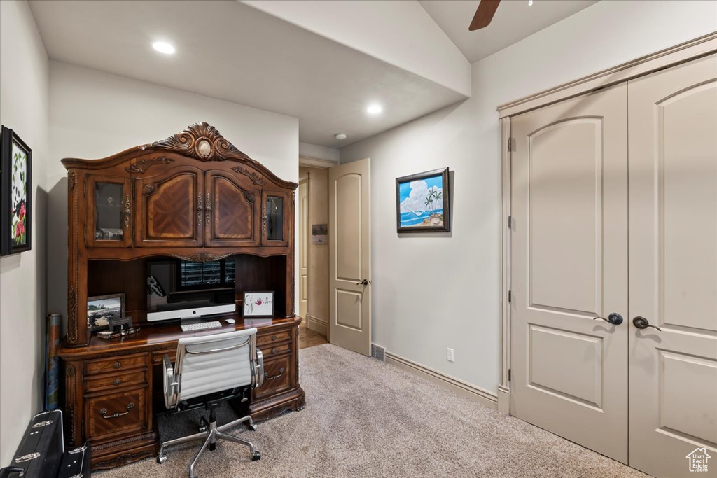 Carpeted home office with built in desk and ceiling fan