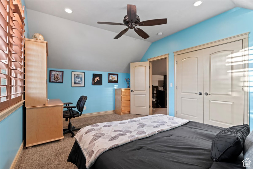 Carpeted bedroom with ceiling fan, a closet, and lofted ceiling