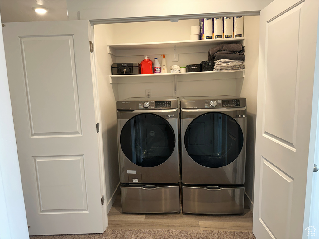 Laundry room with independent washer and dryer and light wood-type flooring