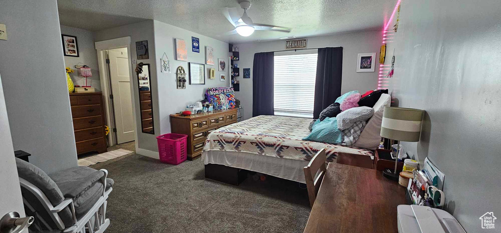 Carpeted bedroom with ceiling fan and a textured ceiling