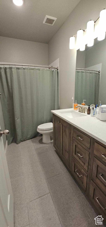 Bathroom with tile flooring, vanity, and toilet