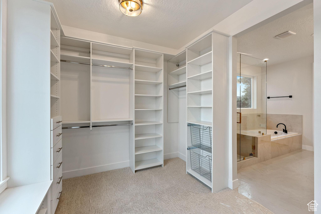 Walk in closet with light colored carpet