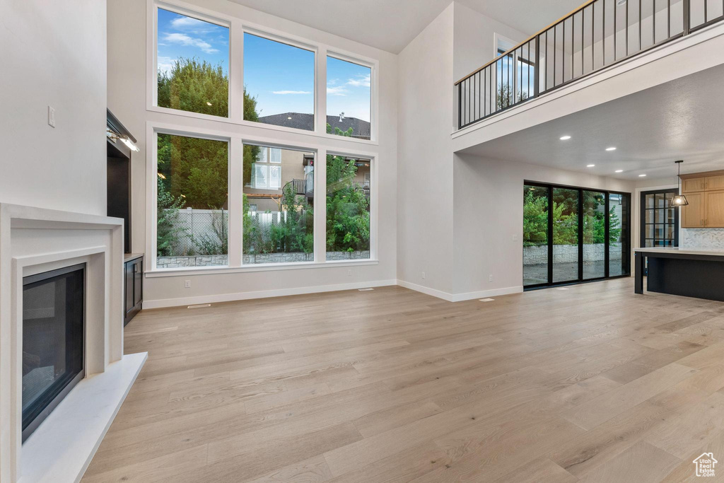 Unfurnished living room with a towering ceiling, plenty of natural light, and light hardwood / wood-style flooring