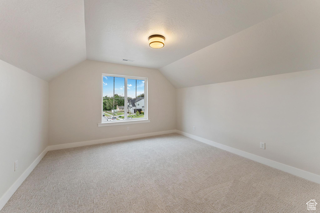 Bonus room featuring lofted ceiling, a textured ceiling, and carpet flooring