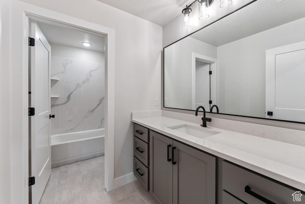 Bathroom with shower / bath combination, a textured ceiling, and vanity