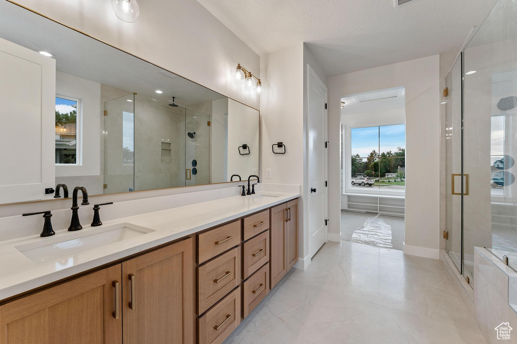 Bathroom featuring tile patterned flooring, double sink vanity, and walk in shower