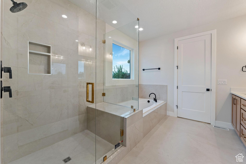 Bathroom with tile patterned floors, independent shower and bath, and vanity