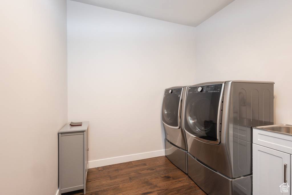 Laundry area featuring cabinets, washer and clothes dryer, and dark hardwood / wood-style flooring