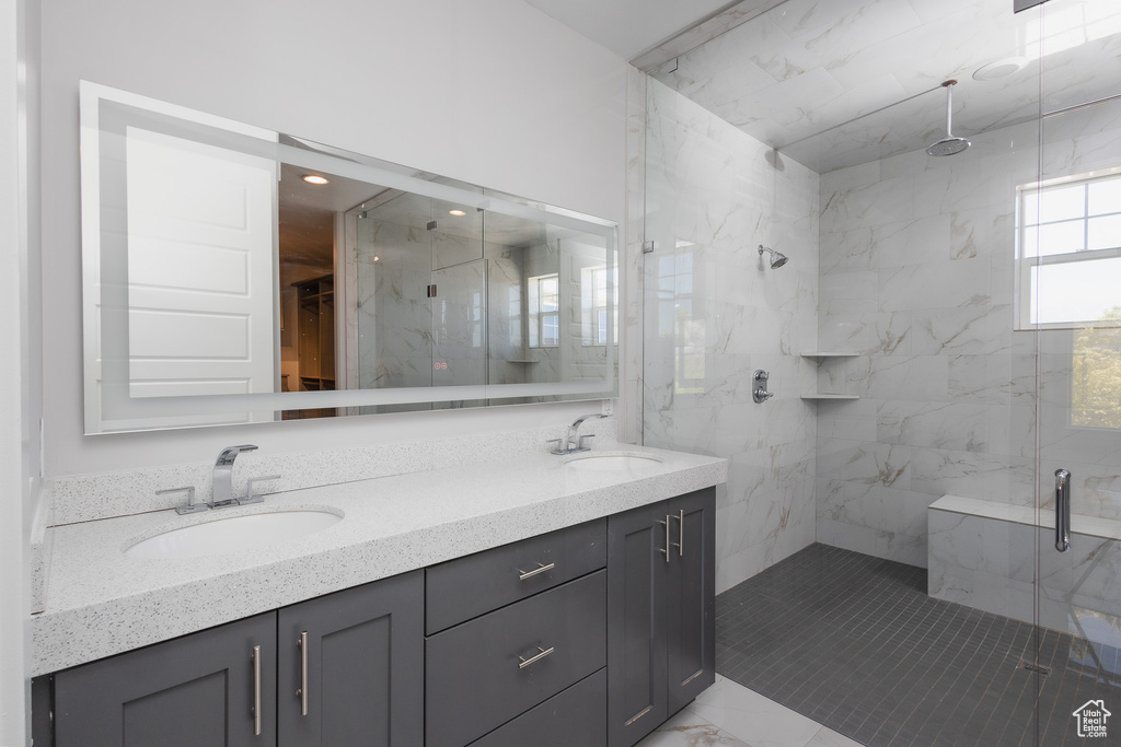 Bathroom with vanity with extensive cabinet space, walk in shower, double sink, and tile floors