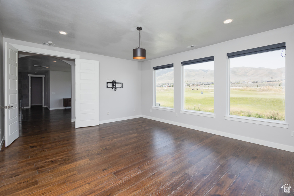 Unfurnished living room with a mountain view and dark wood-type flooring