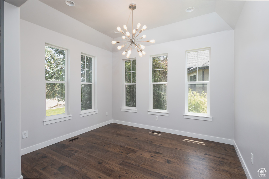 Spare room featuring a notable chandelier, hardwood / wood-style flooring, and a wealth of natural light