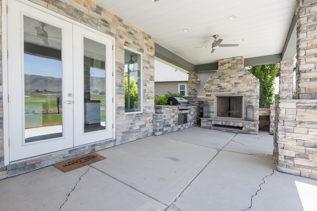 View of patio featuring french doors, a mountain view, grilling area, an outdoor stone fireplace, and ceiling fan