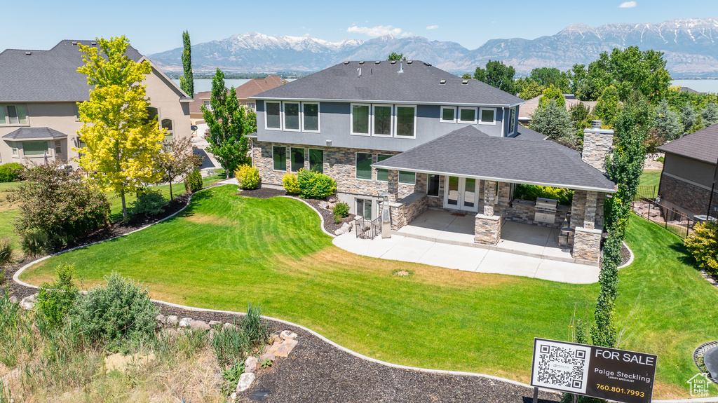 Back of property with a patio area, a mountain view, and a yard